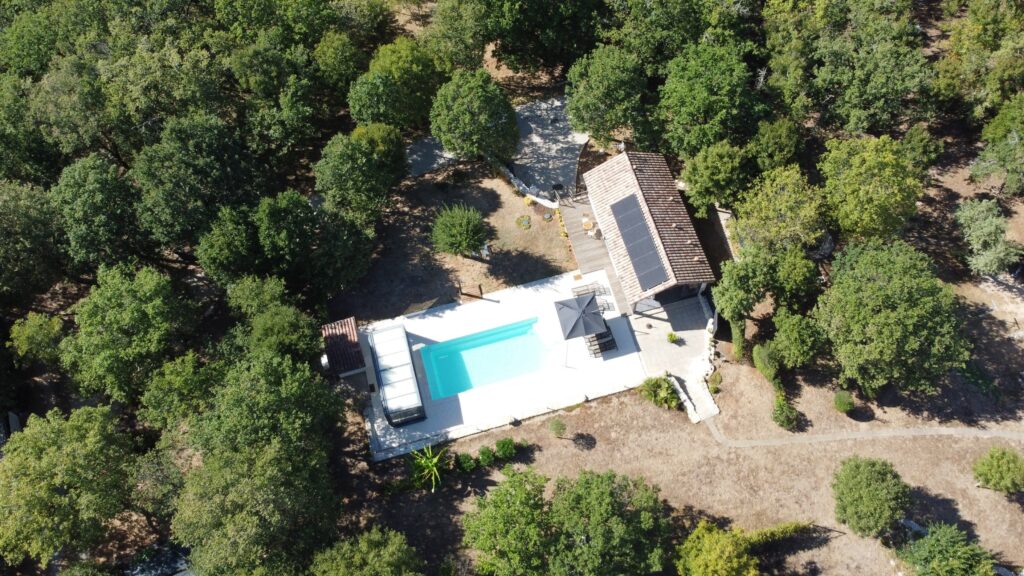 Vue aérienne du Gîte Naturiste DACANIRO, montrant la piscine, les terrasses et l'environnement boisé