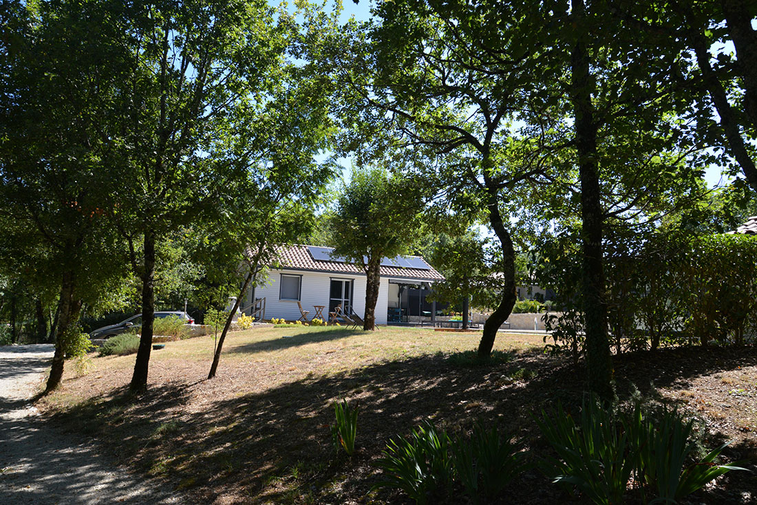 Vue sur le gîte situé au bout d'un chemin boisé, entouré d'arbres